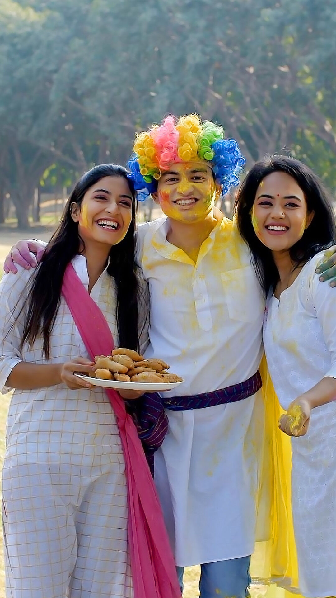 A man and two womens enjoying holi with holi mithai 